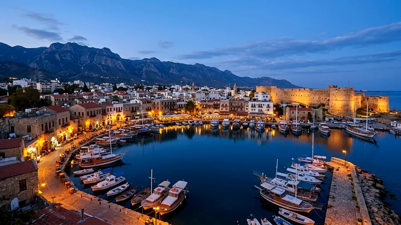 Kyrenia harbour old town and castle at dusk with lights reflecting on water